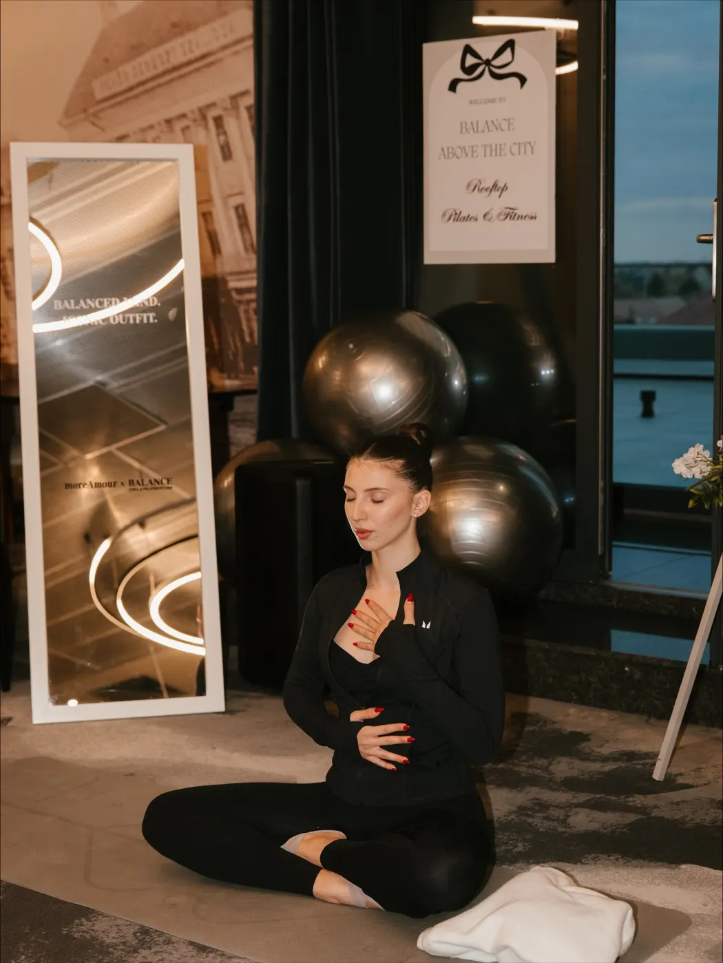 Instructoarea de pilates, cu ochii închiși și mâinile pe piept și pe abdomen, respirând