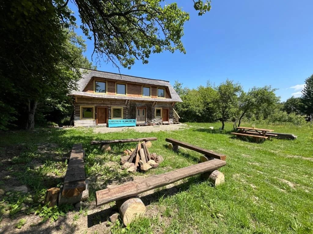 Casa de lemn din Breb, cu locul de foc și băncile din bușteni în față