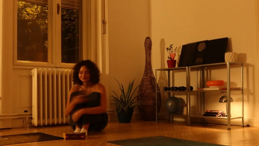 Participantă așezată pe parchet, zâmbind, în lumina caldă a serii din studio