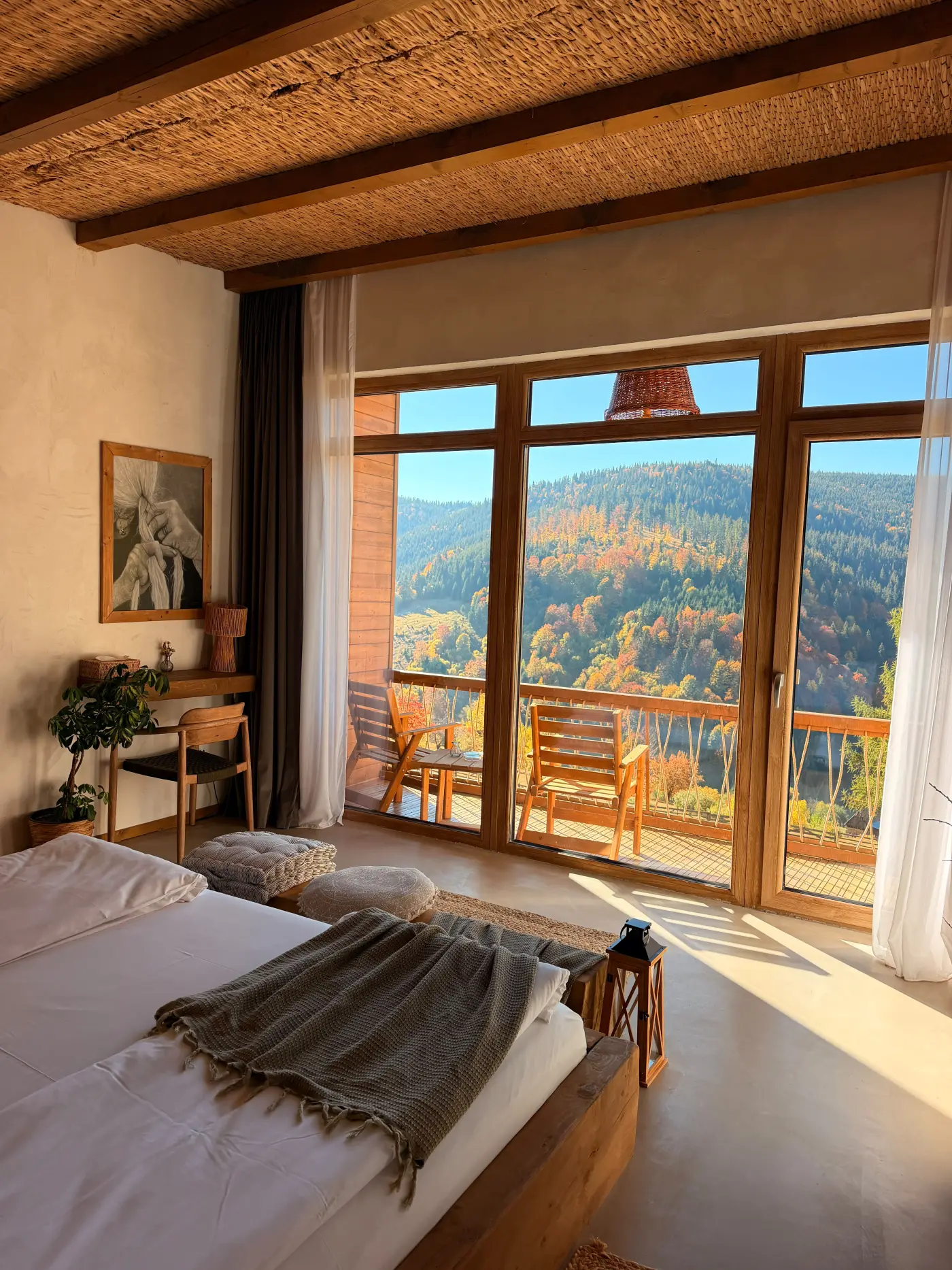 Cameră dublă cu fereastră mare spre balcon și munții în culori de toamnă