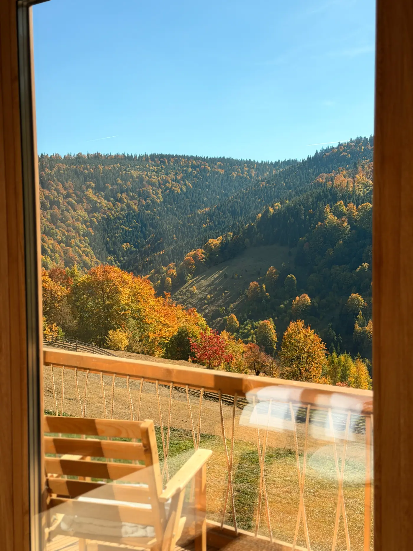 Vedere din cameră spre balcon și dealurile împădurite