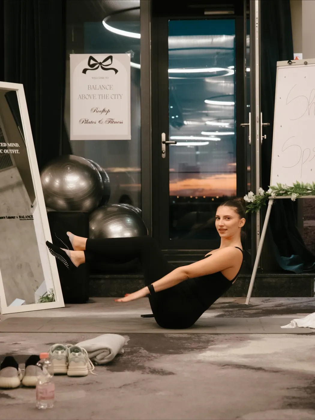 Instructoarea de pilates în teaser, cu apusul în ușa de sticlă din spate