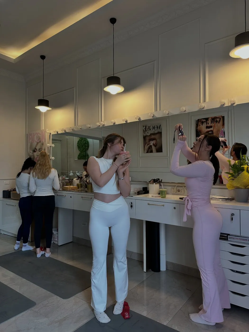 Participante la oglinzile cu becuri, una bea un smoothie, alta face o poză