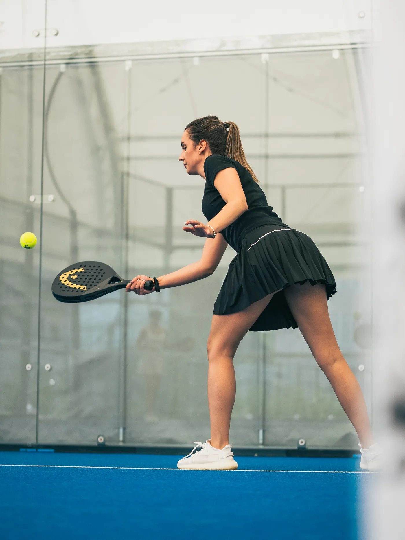 Participantă în negru lovind mingea cu forehand, pe terenul albastru