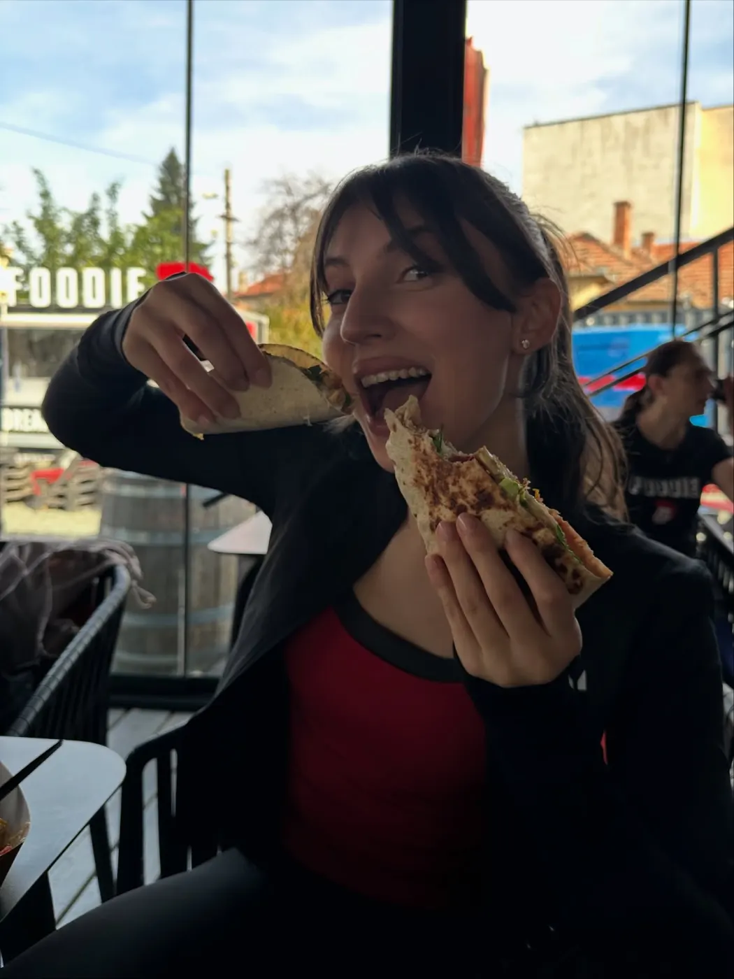 Participantă mușcând dintr-o tortilla, cu un taco în cealaltă mână